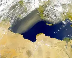 Schema und Satellitenbild einer Scirocco/Chamsin-Lage: links Mittelmeertief und Südströmung von Saharaluft nach Europa, rechts großräumigere südwestliche Höhenströmung.