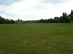 Die Stelle des Amphitheaters, das heute noch als leichte Mulde auf einer Wiese zu erkennen ist.