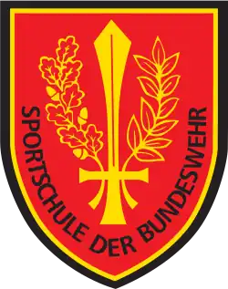 Das heutige Verbandsabzeichen der Sportschule der Bundeswehr, im aktuellen Design. Öl- und Eichenzweig umhüllen wie ein Kranz ein aufrechtstehendes Schwert