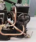 Spritzbürstenvergaser des Stationärmotors von 1887. Der Antrieb im Vordergrund lässt die Bürste rotieren.
