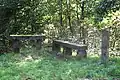 Steinrast im Kottenheimer Wald bestehend aus einer Hochbank und einer dreifüßigen Sitzbank.