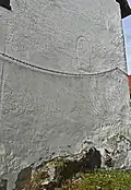 Die auf Fels stehende Ostwand des Chores. Oberhalb der Kette sind die Konturen eines Rundbogenfensters erkennbar
