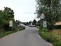 Straße Binsfeld, Einfahrt zur Wohnbebauung von Norden, links Parkplätze der Dauercampinganlage, rechts das erste Haus zwischen Straße und Feldflur