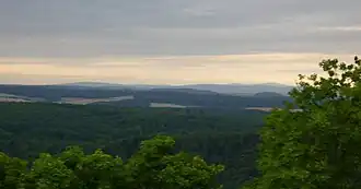 Der Hangelstein (Bildmitte) und Lollarkopf (rechts davon) von Nordnordosten aus; ganz im Hintergrund der Hochtaunus mit dem Großen Feldberg (879 m, hinter Lollarkopf)