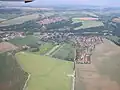 Burgareal in linker Bildmitte neben Wegekreuzung. Burghügel rund mit Bäumen umstanden (Areal des Wassergrabens). 2005.