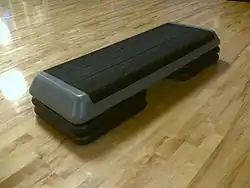 Einstufiges Aerobic-Gerät, das auf einem Holzboden ruht.