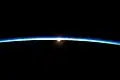Von der ISS in Ebene des Terminators aus gesehen erleuchtet gestreutes Licht die Erdatmosphäre[9]