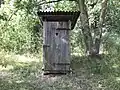 Toilettenhäuschen aus Holz an einem Teich in Brandenburg nahe der Grenze zu Polen