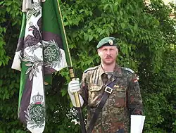 Hauptfeldwebel mit Nach­bildung der Truppen­fahne der Rhein­ischen Jäger (Rhein­isches Jäger-Bataillon Nr.&nbsp;8) HSchBtl 56