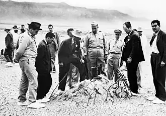 Robert Oppenheimer (heller Hut) und General Leslie Groves (rechts von Oppenheimer) besichtigen die Überreste des Bombenturms