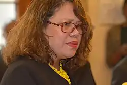 Vivianne Fock Tave. Porträt einer Frau mit schulterlangen Locken und einer Brille mit auffälligem Gestell. 2014