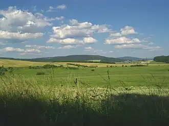Klingeberg (677,2&nbsp;m, Mitte) und Bleßberg (866,9&nbsp;m, mit 195&nbsp;m Antenne, rechts hinten) im Thüringer Schiefergebirge bei Eisfeld. Links geht der Klingeberg in den Eckartsberg (760,4&nbsp;m) über, darunter erkennt man den Ort Waffenrod/Hinterrod auf einer Bergwiese; rechts der Ort Crock und die Trasse der A&nbsp;73 bei Brünn/Thür.