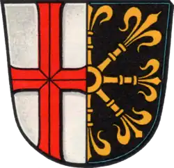 Im gespaltenen Schild vorne in Weiß ein durchgehendes rotes Kreuz, hinten in Schwarz ein halber goldener Lilienzepterstern am Spalt (Bleidenstadt)
