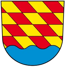 Über blauem Wellenschildfuß von Gold (Gelb) und Rot mit drei Teilungen schräg gerautet (Guggenhausen)