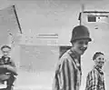 Befreite jüdische Gefangene - einer trägt einen deutschen Stahlhelm - lächeln in die Kamera
