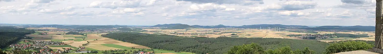 Nordostblick von der Weidelsburg: Links vorne der Ippinghäuser Grund mit Ippinghausen und dem tiefer gelegenen Weiler Leckringhausen, schräg rechts dahinter Wolfhagen und der Ofenberg (372,5&nbsp;m; 6,8&nbsp;km entfernt) rechts der Stadt und am Westrand des Altenhasunger Grabens; weiter rechts der Isthaberg (523,1&nbsp;m; 7,1&nbsp;km) und schließlich die Isthaebene mit Bründersen vor Istha vor Oelshausen (Mitte) und Altenstädt vor Balhorn (rechts), die zum Ippinghäuser Grund hin vom flacheren, bewaldeten Höhenzug des Rauenstein (366,4&nbsp;m; 2,4&nbsp;km) gerahmt wird. Hintere Reihe: Links hinter den Windkraftanlagen Stromberg (362,2&nbsp;m; 14,0&nbsp;km) und Heidelbeerenberg (398&nbsp;m; 13,3&nbsp;km), rechts dahinter der Desenberg (343,6&nbsp;m; 25,6&nbsp;km); links des Ofenbergs der Warteberg (419&nbsp;m; 9,8&nbsp;km), zwischen beiden der Escheberg (448,9&nbsp;m; 16,0&nbsp;km), dem sich nach rechts der Heuberg (392&nbsp;m; 30,9&nbsp;km) links hinter dem Malsberg (405,6&nbsp;m; 17,3&nbsp;km) und schließlich Westberg (340&nbsp;m; 31,4&nbsp;km) und Schöneberg (323&nbsp;m; 33,2&nbsp;km) bei Hofgeismar anschließen; in der Bildmitte, links hinter dem Isthaberg, das Bärenberg-Massiv mit Kleinem Gudenberg (531,8&nbsp;m; 13,7&nbsp;km), Großem Gudenberg (568,7&nbsp;m; 13,7&nbsp;km) und Großem Bärenberg (600,7&nbsp;m; 12,3&nbsp;km) mit Funk- und Aussichtsturm sowie, rechts des Isthabergs, dem Rohrberg (516,7&nbsp;m; 11,9&nbsp;km); weiter rechts Bosenberg (471,5&nbsp;m; 10,7&nbsp;km) und, hinter dem Burghasunger Berg (479,7&nbsp;m; 10,6&nbsp;km) der Dörnberg (578,7&nbsp;m; 16,7&nbsp;km) nebst Hohlestein (476,6&nbsp;m; 17,5&nbsp;km) und Katzenstein (gut 420&nbsp;m; 17,3&nbsp;km); hinter den Windkraftanlagen schließlich der Hohe Habichtswald (614,8&nbsp;m; 15,1&nbsp;km) hinter Hundsberg (496&nbsp;m) und Wattenberg (516,2&nbsp;m; 9,5&nbsp;km) mit Martinhagen und Breitenbach rechts davon und schließlich Saukopf (511,4&nbsp;m; 12,7&nbsp;km) und Schwengeberg (556,7&nbsp;m; 14,0&nbsp;km) in den Langenbergen. Hinterer Horizont: Links vom Stromberg der Winterberg (429,1&nbsp;m; 76,6&nbsp;km), Großer Pulskopf (447,7&nbsp;m; 69,5&nbsp;m) zwischen Strom- und Heidelbeerenberg sowie Köterberg (495,8&nbsp;m; 65,9&nbsp;km) rechts des Desenbergs (alle Lipper Bergland); zwischen Warteberg und Bärenbergmassiv im Hintergrund der unauffällige Solling (bis 527,8&nbsp;m; am Höhenschwerpunkt gut 65&nbsp;km); davon unmittelbar links der Gudenberge der Große Steinberg (492,5&nbsp;m; 60,0&nbsp;km); zwischen Dörnberg und Hohem Habichtswald der Dransfelder Stadtwald mit dem Hohen Hagen (492,5&nbsp;m; 48,6&nbsp;km), links davon der fast nie (auch hier nicht) sichtbare Brocken (1141,2&nbsp;m; 117,4&nbsp;km); zwischen Hohem Habichtswald und Saukopf der Kaufunger Wald mit dem rechts als Kuppe erkennbaren Bilstein (641,2&nbsp;m; 44,7&nbsp;km), zwischen Saukopf und Schwengeberg der Hohe Meißner (bis 753,6&nbsp;m; 49,8&nbsp;km).