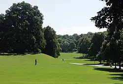 Ein geschwungenes Tal mit einer steilen und einer flachen Flanke, beidseitig mit Bäumen bestanden