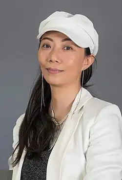 Portrait von Ying Wang vor grauem Hintergrund mit weißer Mütze