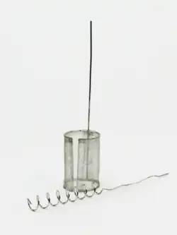 Auf Weißem Untergrund zwei metallisch glänzende Elektroden aus paltiniertem Draht. Eine liegt und ist im unteren Teil zu einer Spirale gebogen und in der oberen Hälfte gerade. Die zweite steht und besteht aus einem untersten Teil, der aus einem rund gebogenem Netz besteht, der obere Teil ist ebenfalls ein gerader Draht.