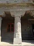 Säule mit gedrehten Kanneluren, skulptiertem Kapitell und Architrav. Rechts befindet sich der Eingang zur Höhle