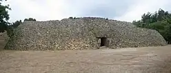 Gesamtansicht des etwa 8&nbsp;m hohen Cairns. Der beinahe kreisrunde Bau mit einem Durchmesser von etwa 50&nbsp;m war ansatzweise dreistufig gestaltet und wurde entsprechend rekonstruiert.