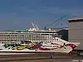 Die Norwegian Jewel im Größenvergleich mit Menschen und einem Toilettenhäuschen