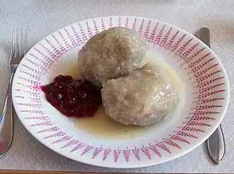 Kroppkaka (mit Speckwürfeln und Zwiebeln im Inneren) serviert mit Preiselbeeren und geschmolzener Butter.