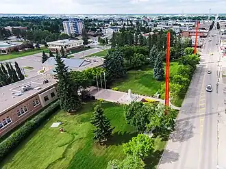 Die roten Pfähle sind die optischen Grenzmarkierungen entlang der 50th Avenue in Lloydminster; links das in Alberta liegende Rathaus / Alberta
