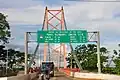 Das Hinweisschild auf der 723 m langen Billinghurst-Brücke über den Rio Madre de Dios in Puerto Maldonado zeigt die Entfernung der brasilianischen Grenze mit 325 km und von dort Rio Branco mit 230 km an.